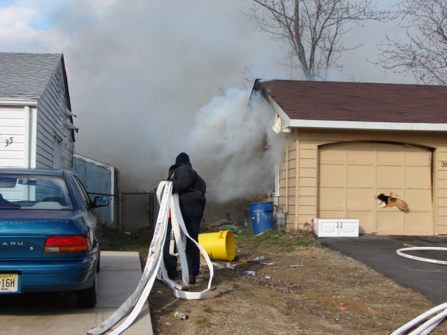 Firefighter Bryan Bennett pulls a second handline at a house fire in Pennypacker Park