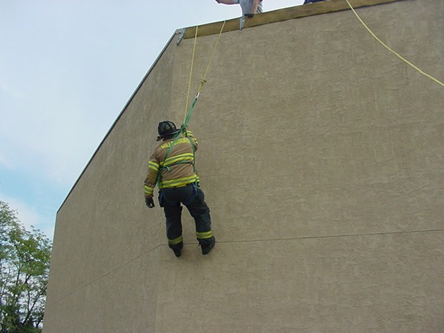 Firefighter J. Clark using his personal harness and rope to simulate escaping from a roof