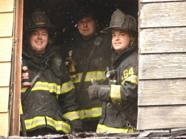 Firefighters J. Clark, Friddell, and Fresco performing overhaul at a house fire on Hadley Lane